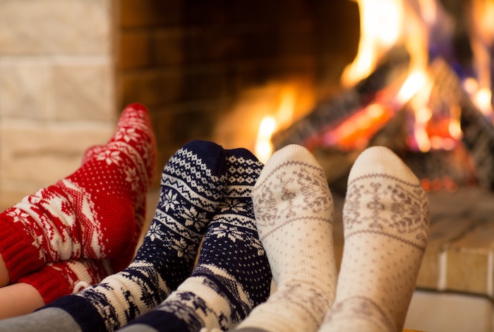 Three pairs of socks curled by a fire during the wintertime.