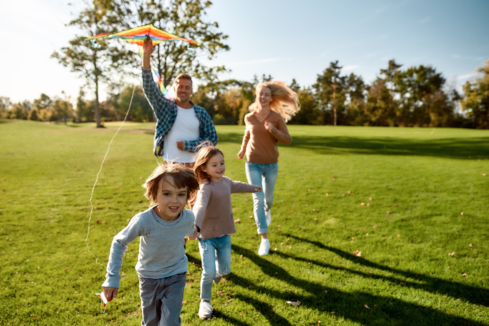 Young, smiling family outdoors in a park during the springtime.