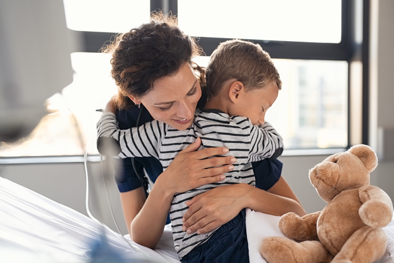 Young woman pediatrician hugging a young child in a doctor’s office