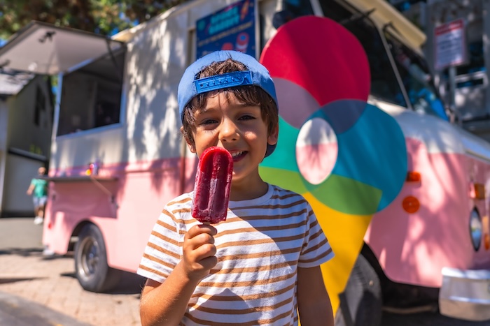 Young ethnically ambiguous boy eating a popsicle on a hot summer day.