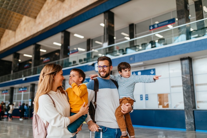 Caucasian parents holding their two little boys in an airport.