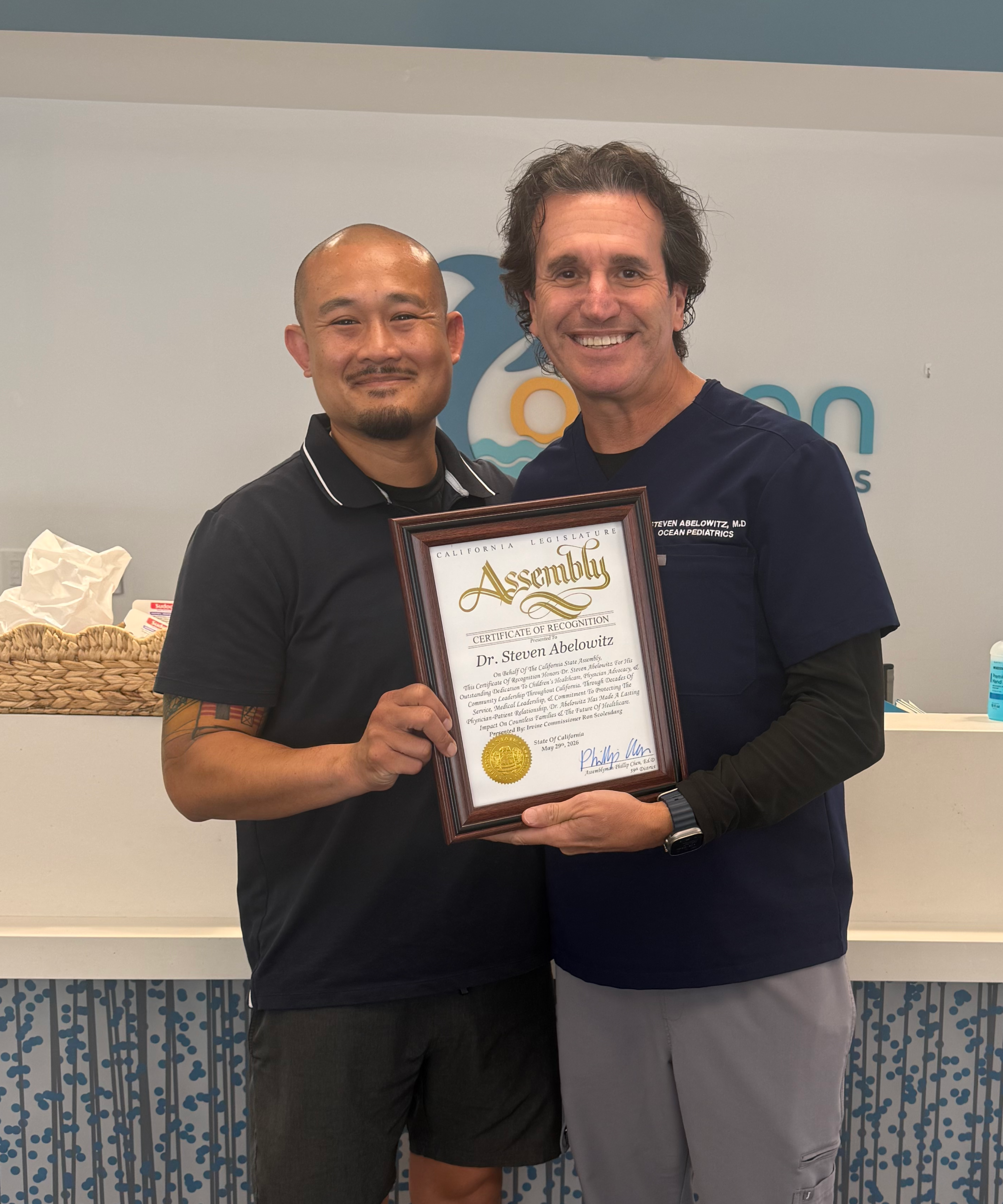 Orange County pediatrician, Dr. Steven Abelowitz, being presented with an award by Irvine Commissioner, Ron Scolesdang.