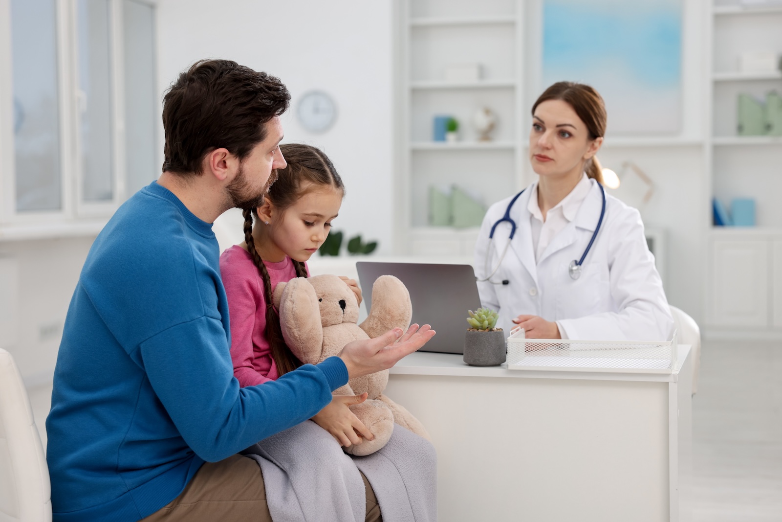 Young child and their parent looking unhappy at a pediatrician office.