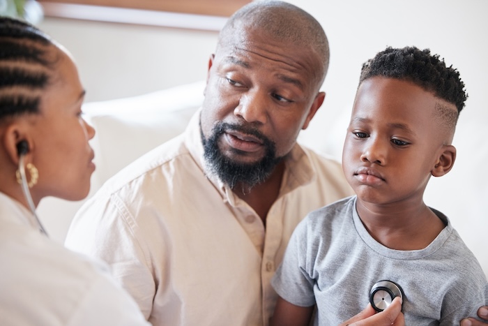 Black father discussing his child’s health at his child’s pediatric office.