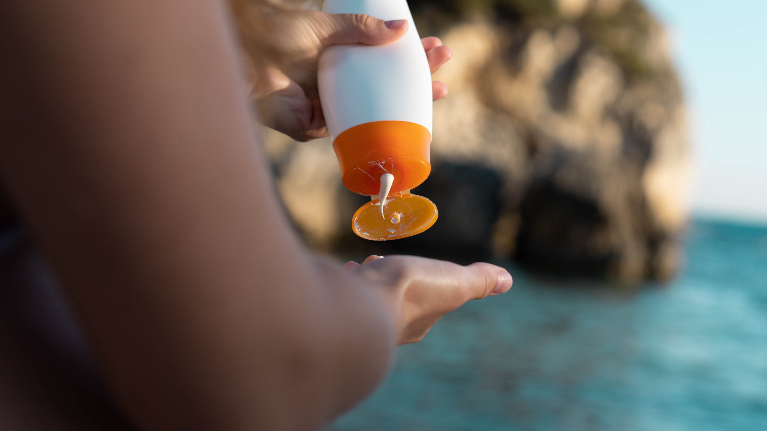 Closeup of person applying sunscreen at the beach.