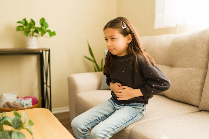 Little girl holding her tummy in pain.