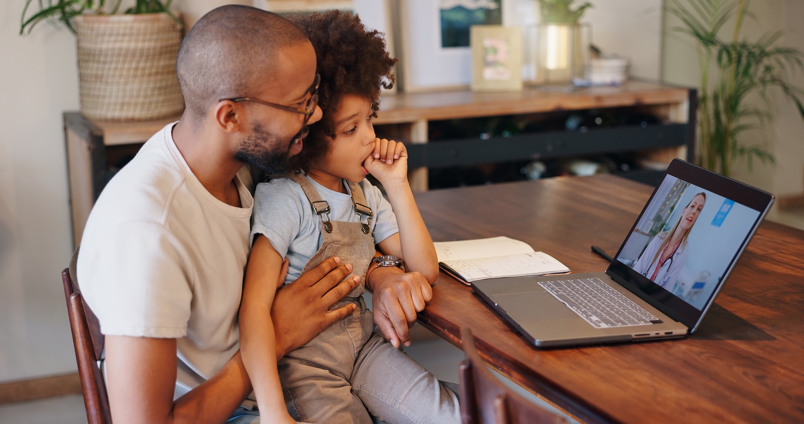 Black father and young son on a video call, telehealth appointment with their pediatrician.